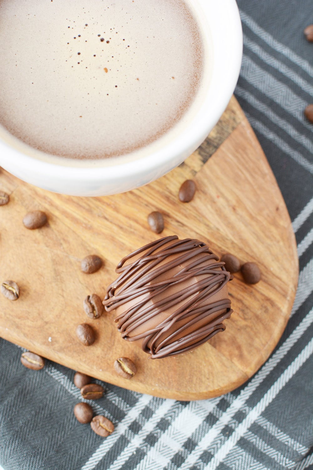 Overhead image of a coffee bomb next to mug of coffee. Coffee beans are on the table and a blue napkin.