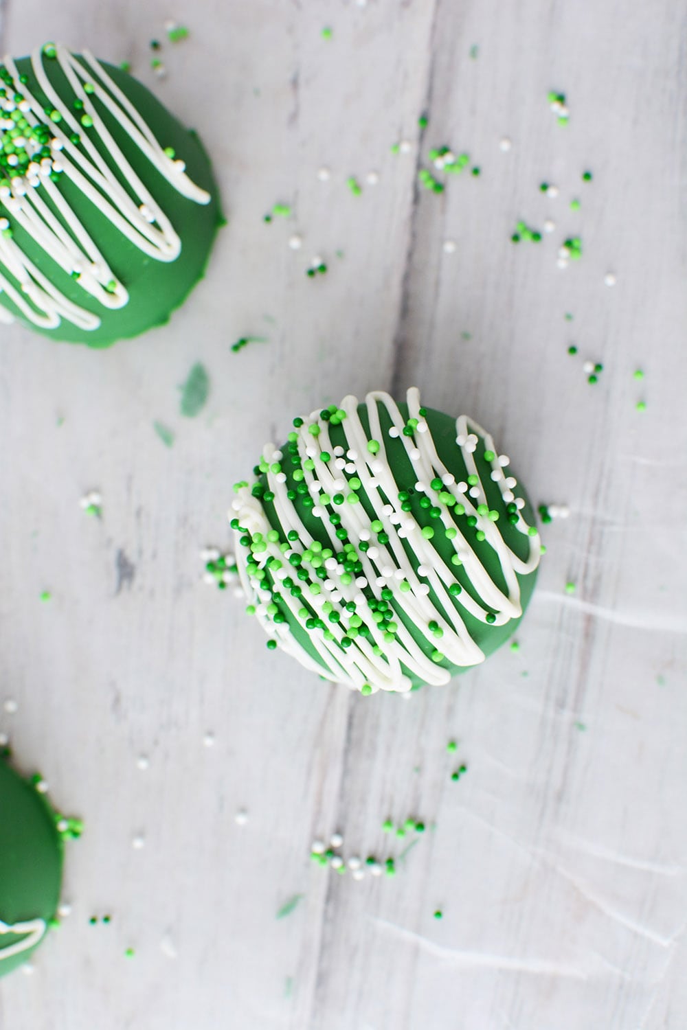 Topping a green hot chocolate bomb with St. Patrick's Day sprinkles.