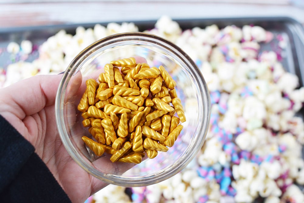 Candy gold unicorn horns over a baking sheet of popcorn.