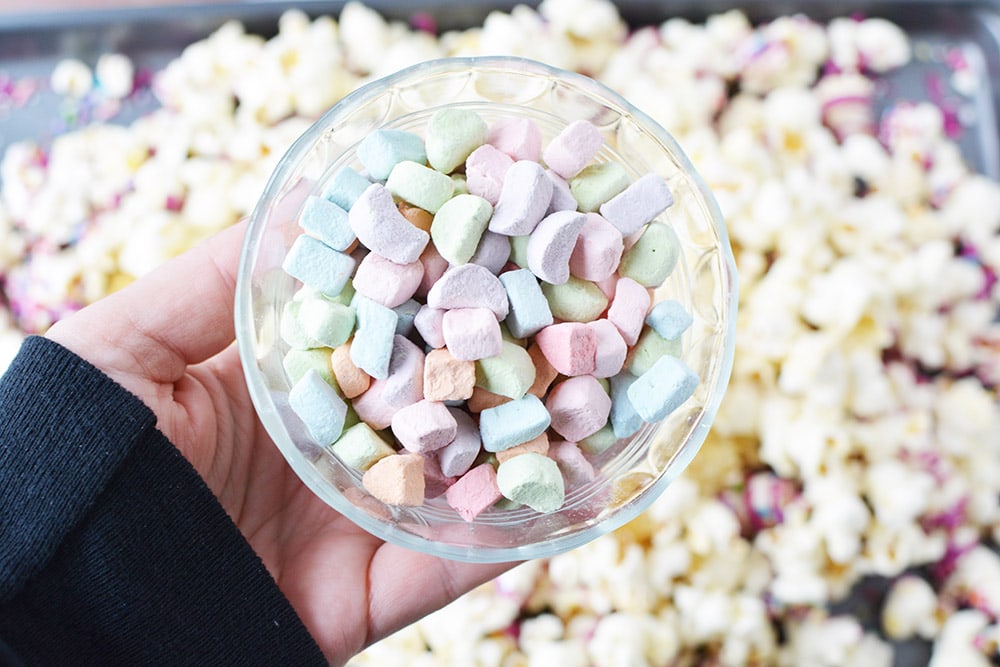 Rainbow marshmallows in a bowl over popcorn.