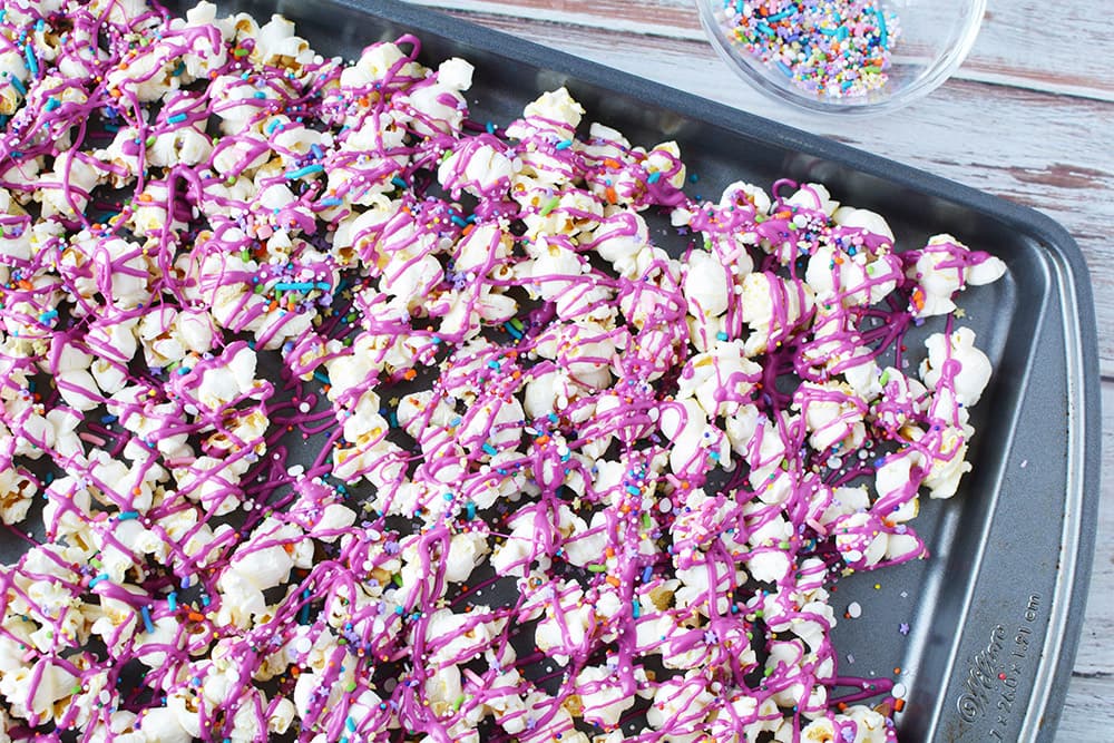 Pink candy melts drizzled over popcorn.