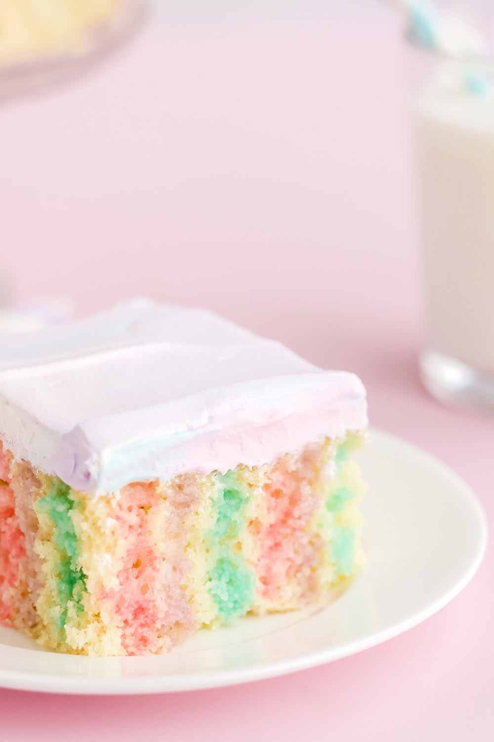 Unicorn poke cake on a white plate.