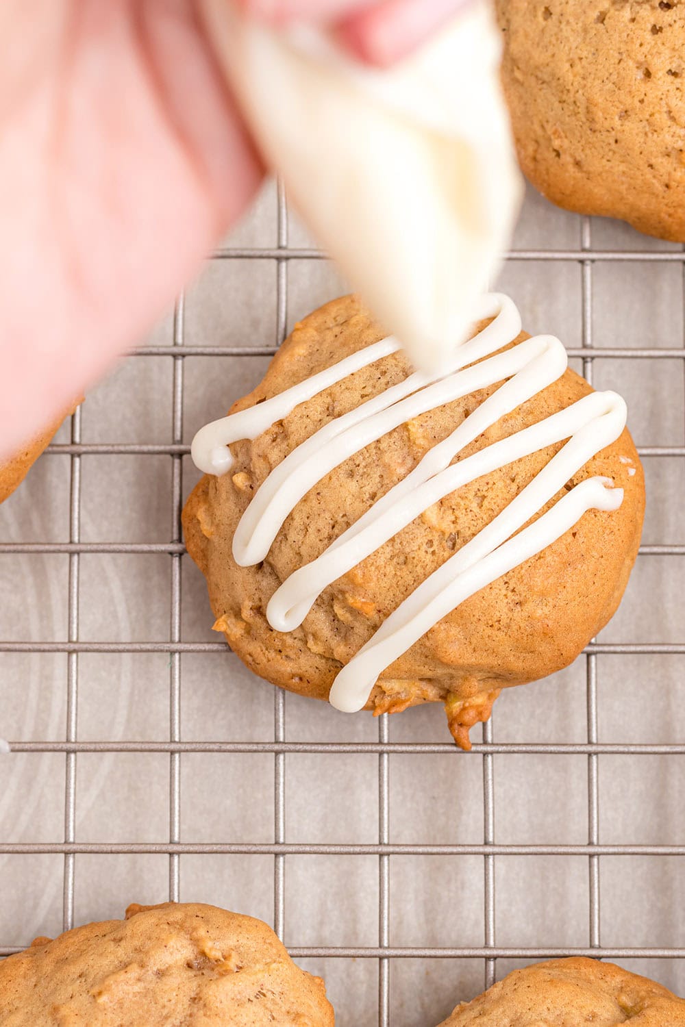 Piping glaze on cookies.