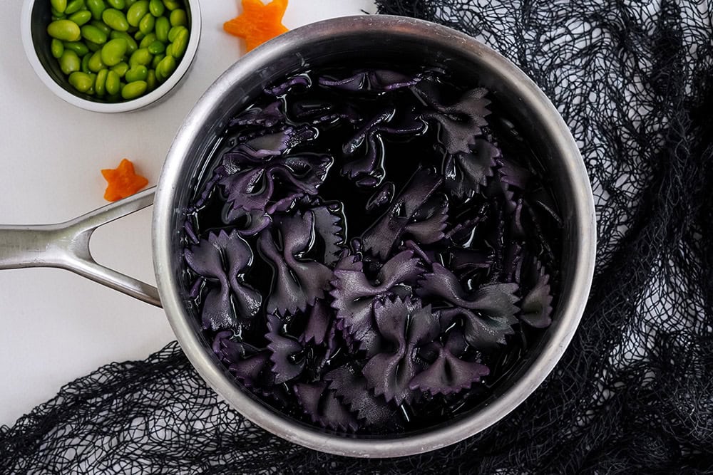 Bowtie pasta soaking in black food coloring.