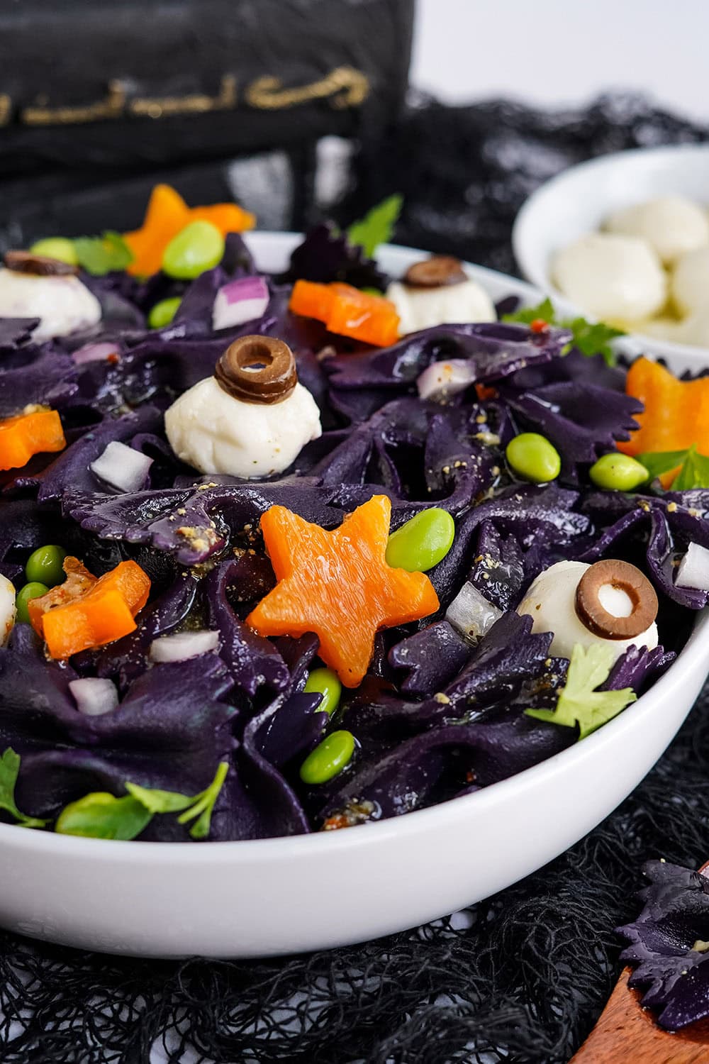 Star peppers and mozzarella eyeballs on top of black bat pasta for Halloween.