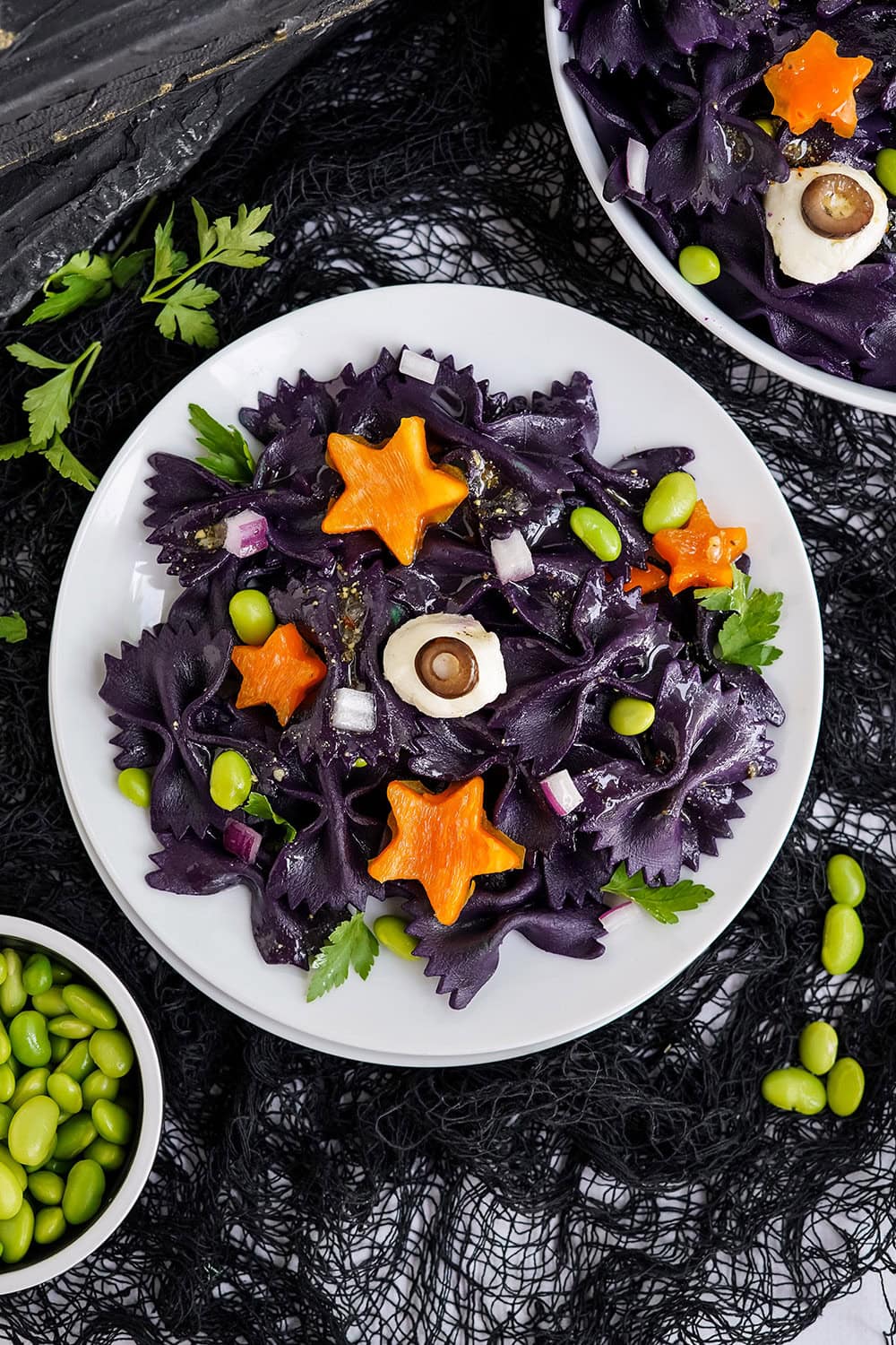 Overhead image of halloween pasta salad with bowls of ingredients on the table.