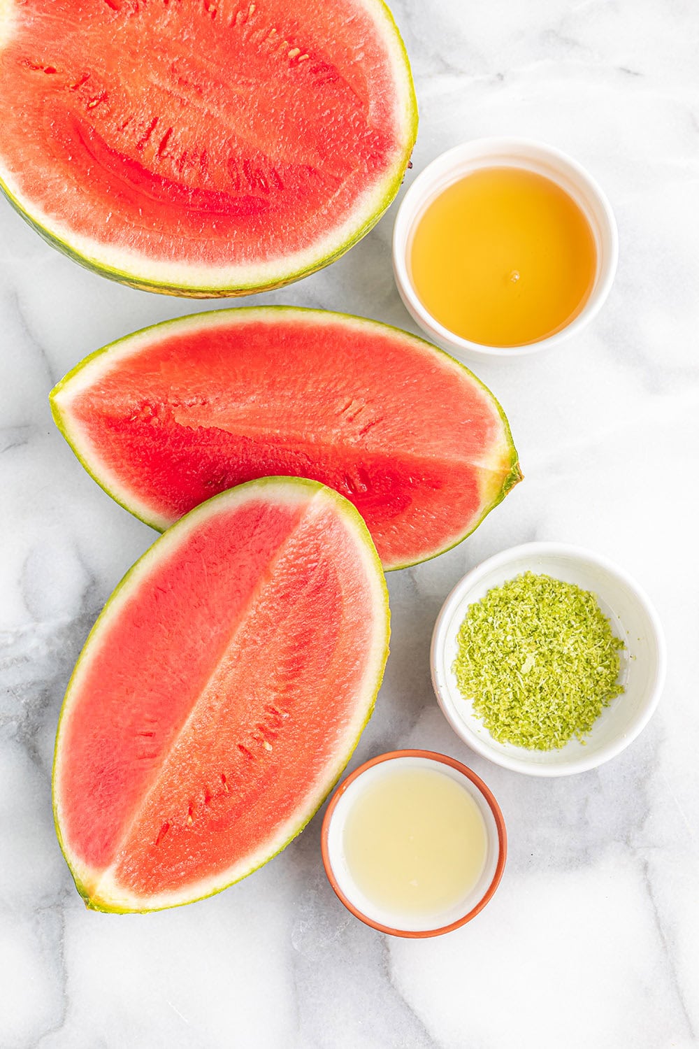 Slices of watermelon, lime zest, lime juice, and agave nectar on a table.