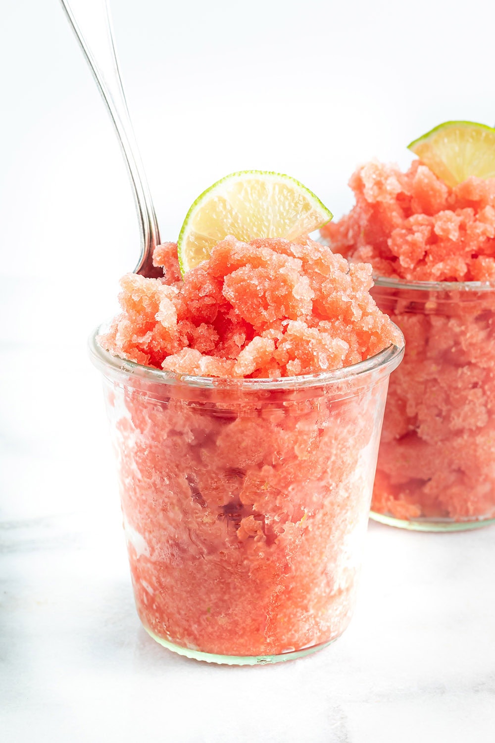 Watermelon lime granita in a cup with a spoon in it.