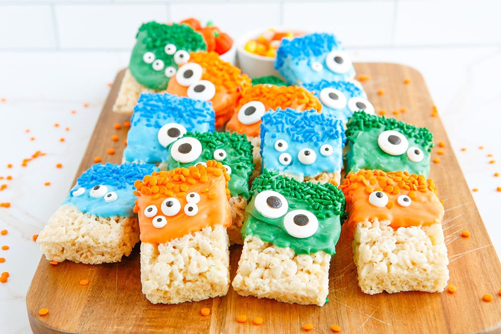 Rice Krispies treats decorated as monsters lined up on a board.