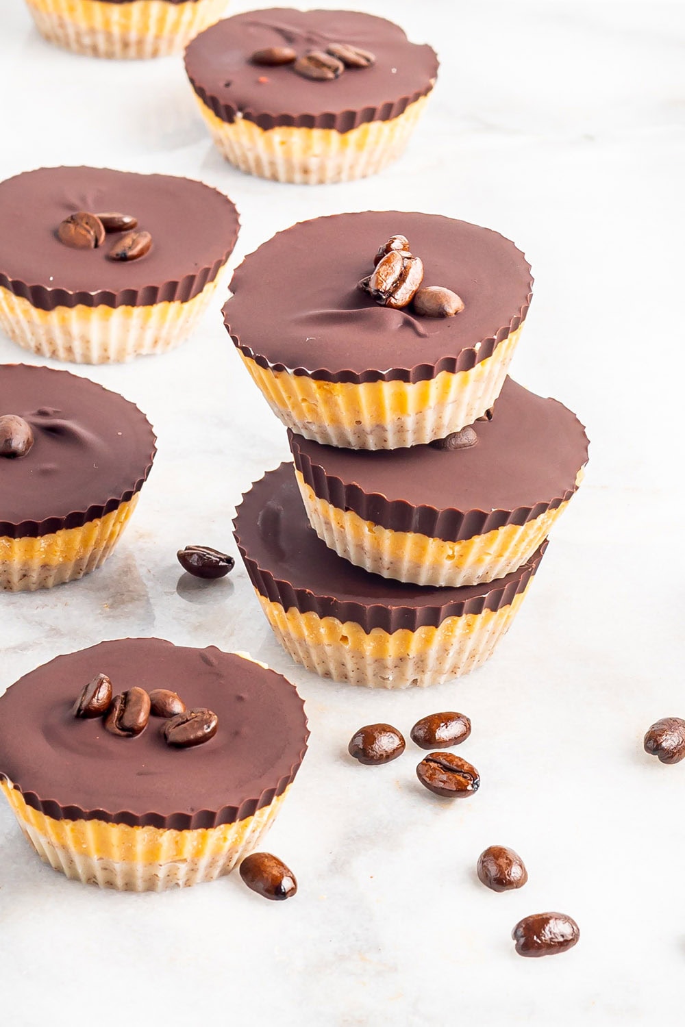 Chocolate pumpkin candies sitting on top of each other with espresso beans on the table.