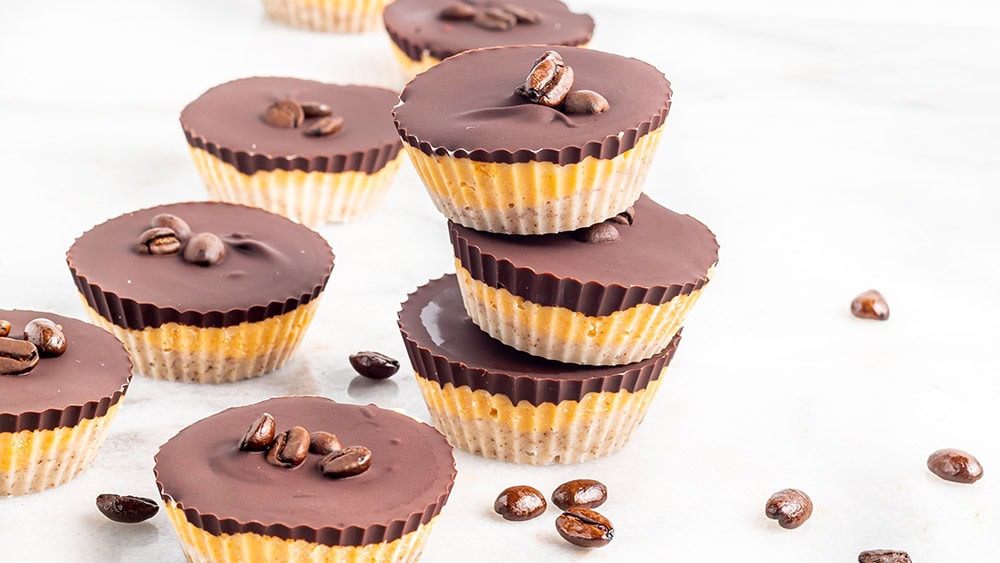 Stacked chocolate candy cups with coffee beans on the table.