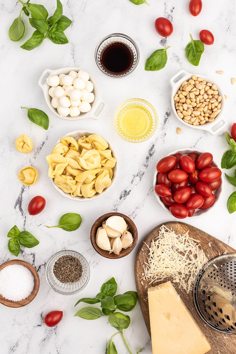 Tomatoes, cheese, basil, and other caprese salad ingredients on a table. 