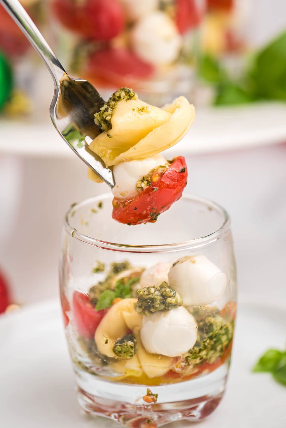 Fork full of caprese salad above the glass it's served in. 