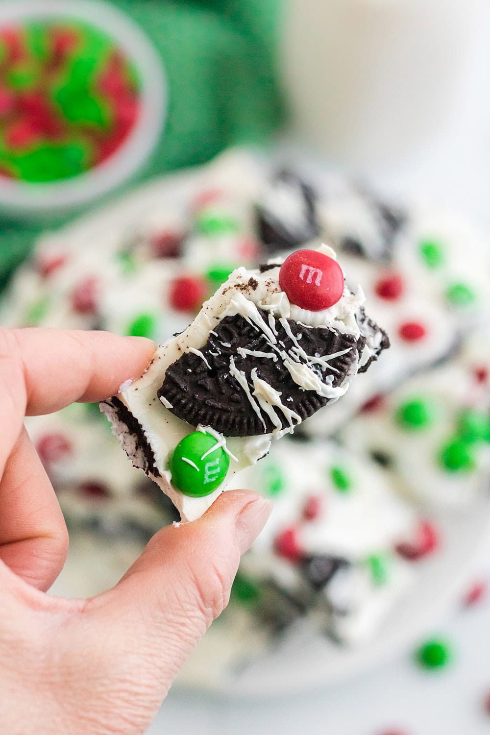 Holding a piece of Christmas OREO bark candy.