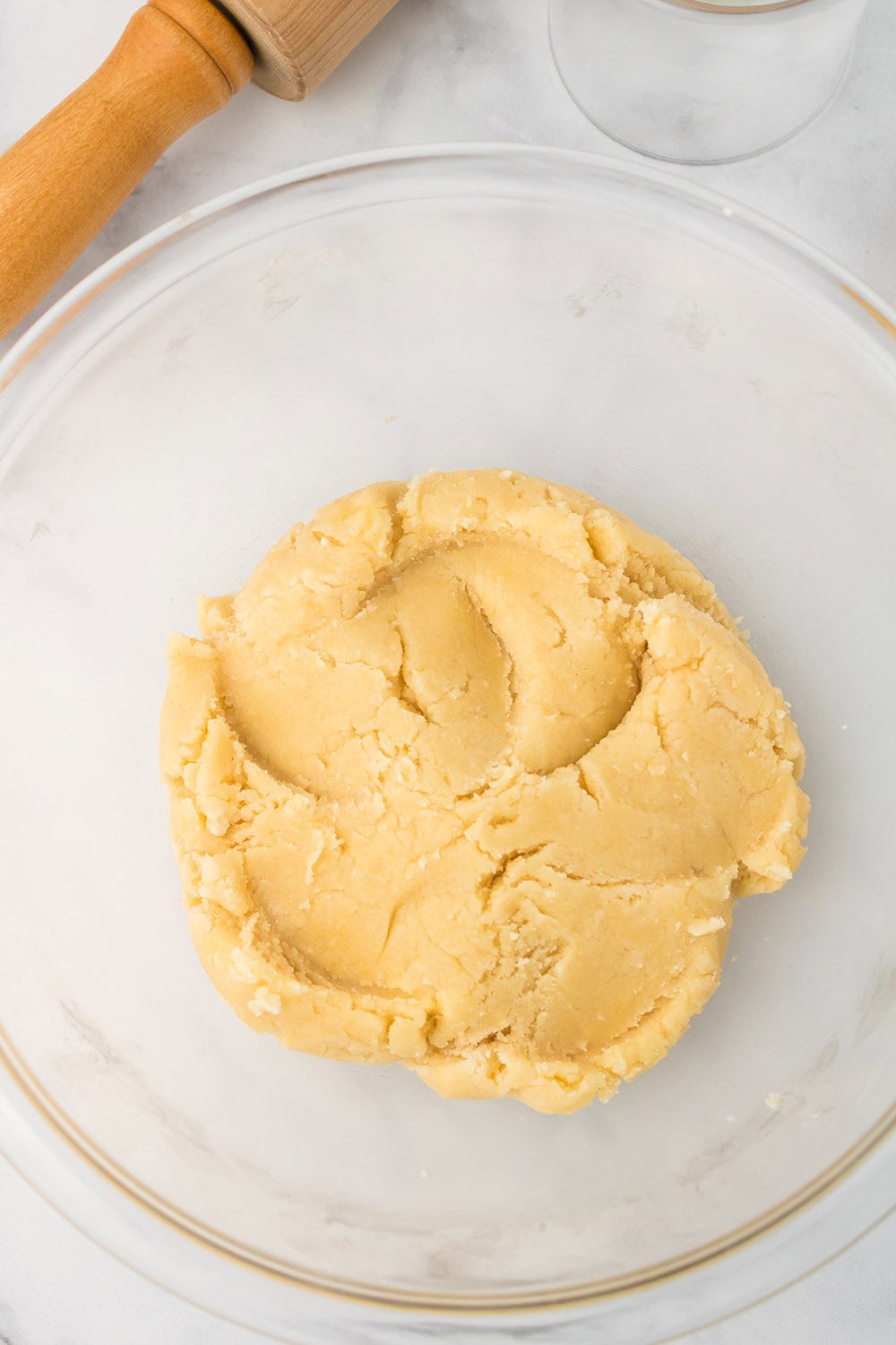 Sugar cookie dough in a clear mixing bowl. 
