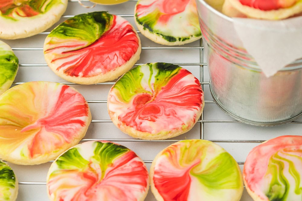 Green and red marble cookies sitting next to a tin bucket. 