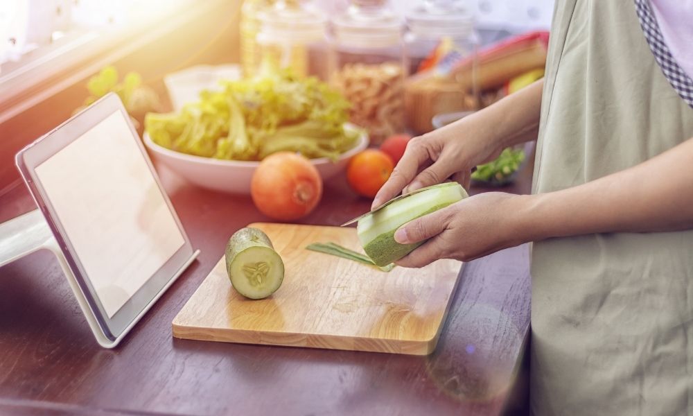 Chopping vegetables in front of a tablet.