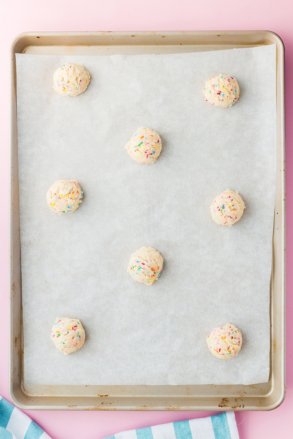 Cookie dough balls on a baking sheet with parchment paper.