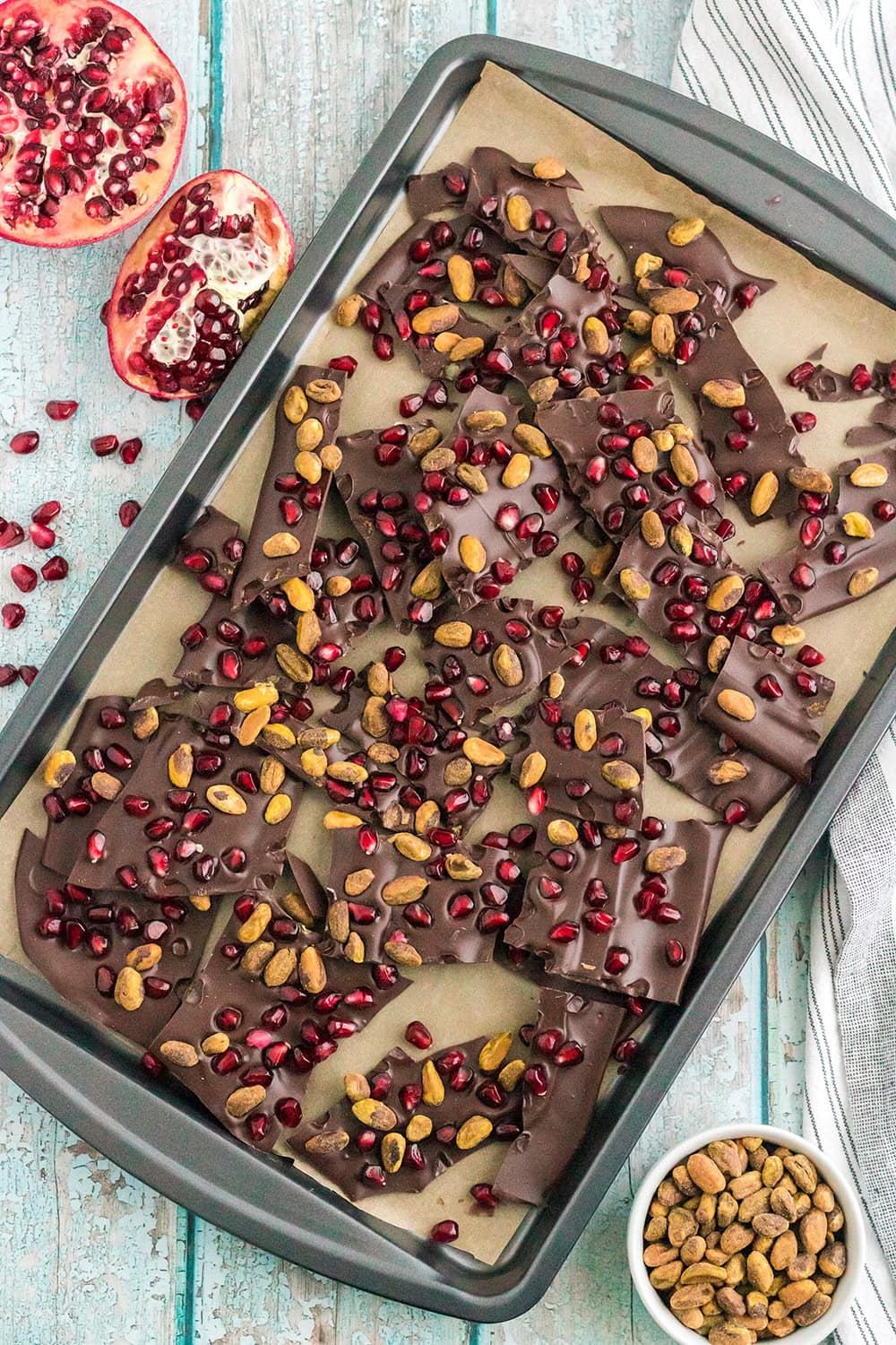 Chocolate pomegranate bark broken into pieces on a baking sheet. o