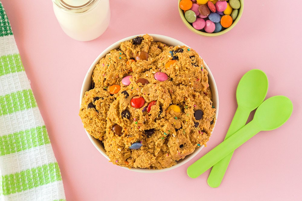 Overhead image of cookie dough next to green spoons and milk. 