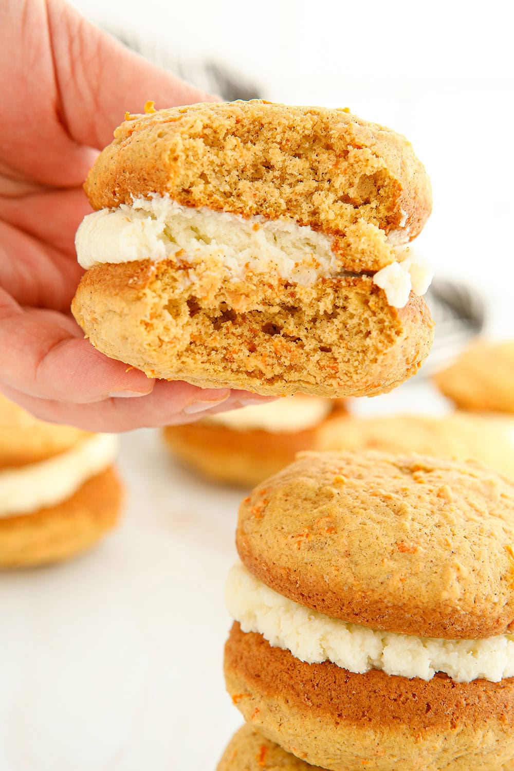 Holding a carrot whoopie pie with a bite taken out of it. 