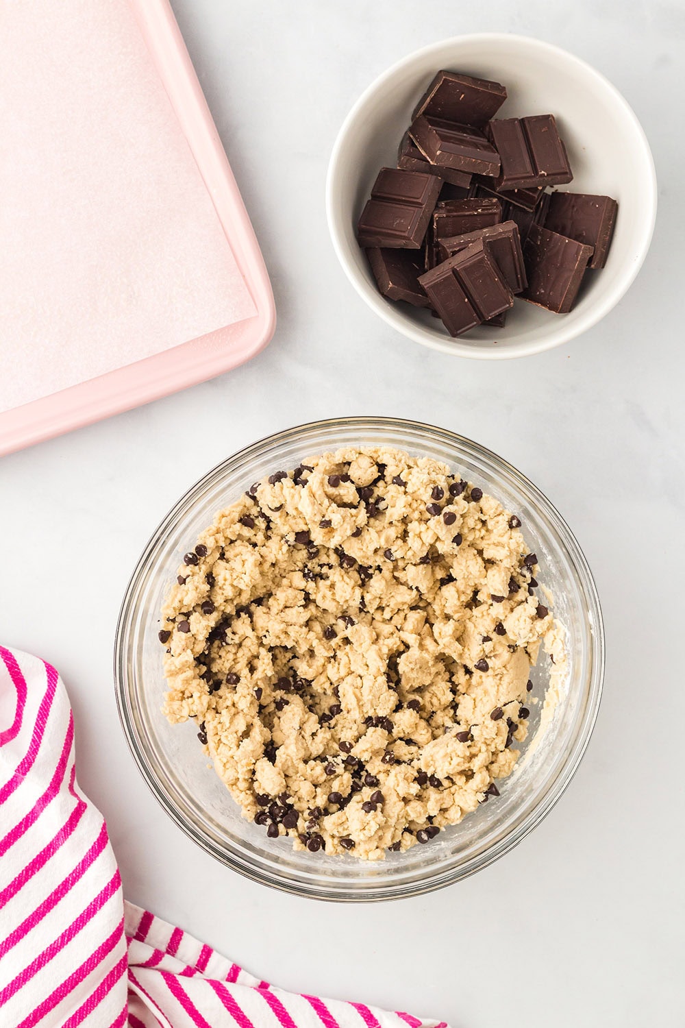 Cookie dough and chunks of chocolate in bowls.