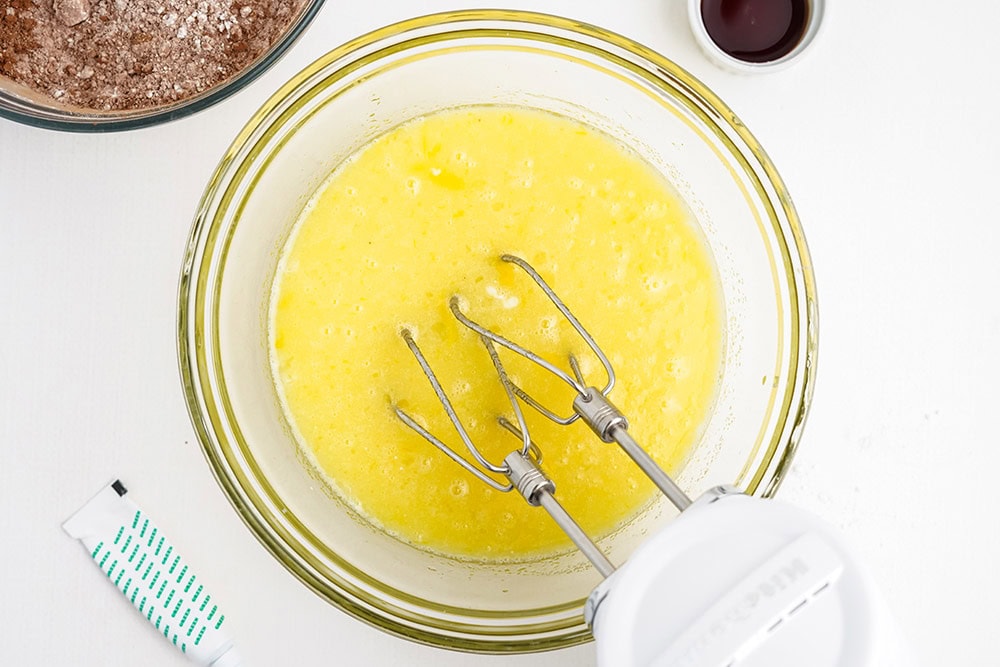 Cupcake batter in a bowl with a mixer in it.