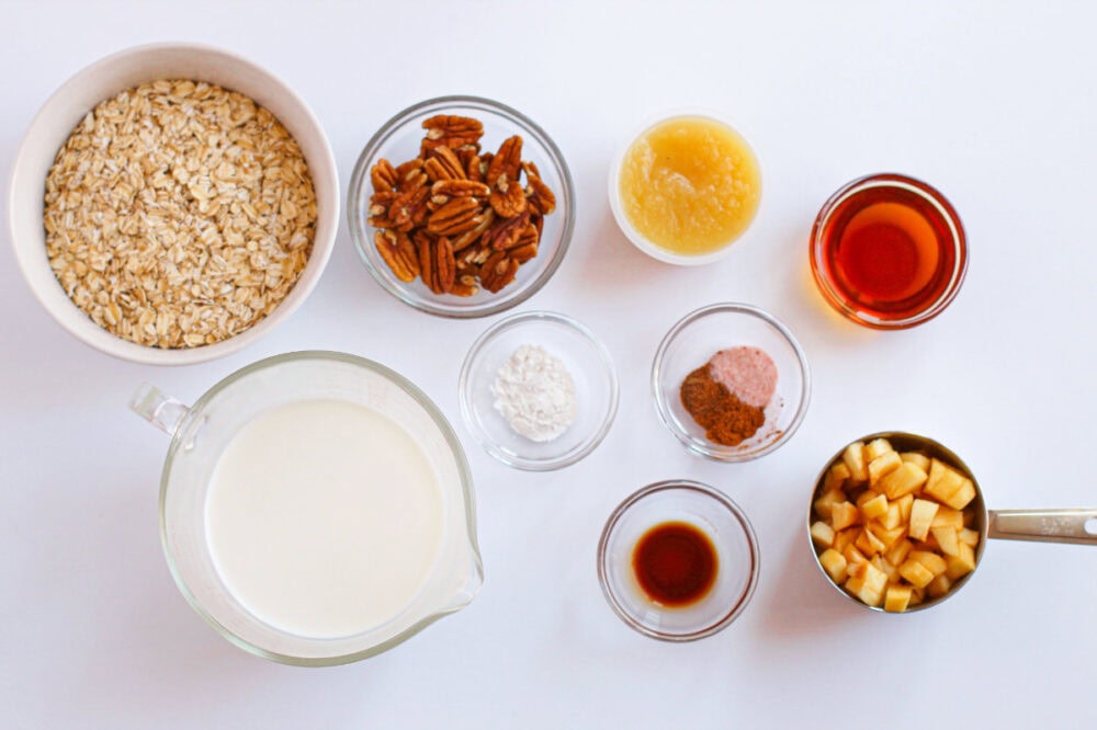 Oats, apples, and spices in bowls to make baked oatmeal.
