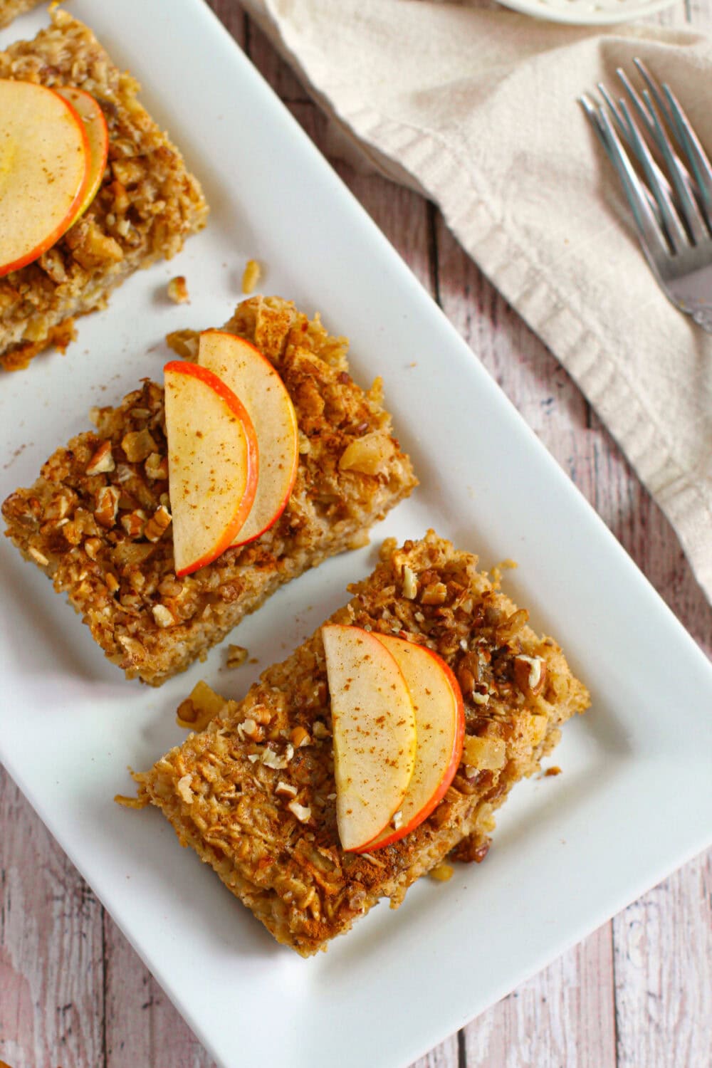 Slices of apple baked oatmeal on a white dish.