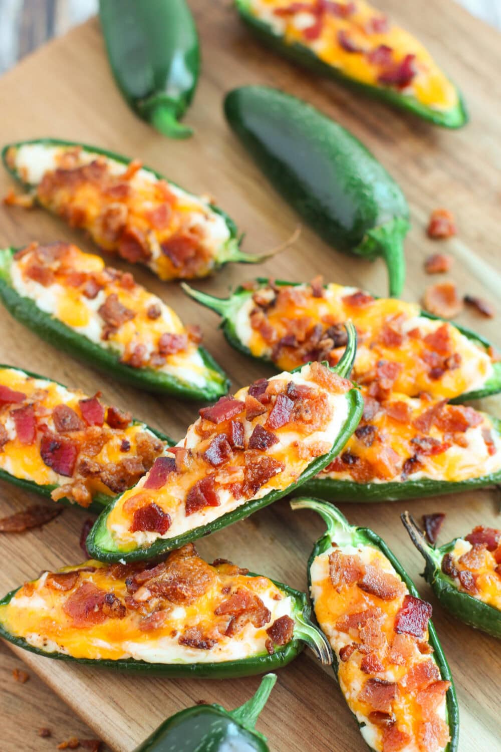 Several bacon jalepeno poppers on a cutting board. 
