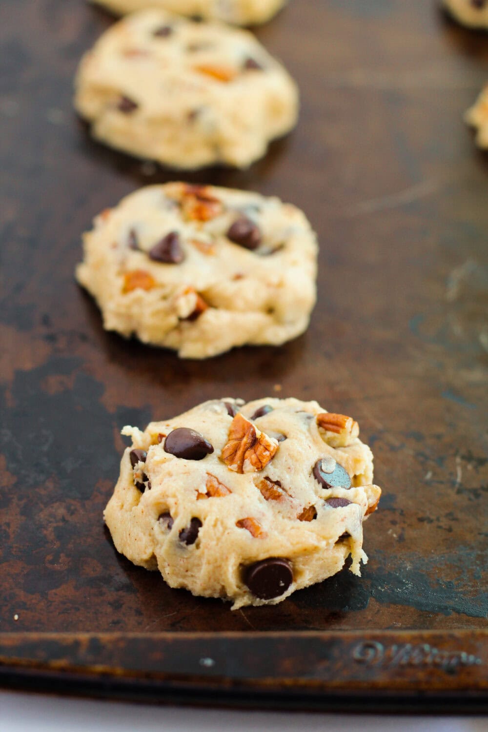 Chocolate chip pecan cookie dough batter on a baking sheet.