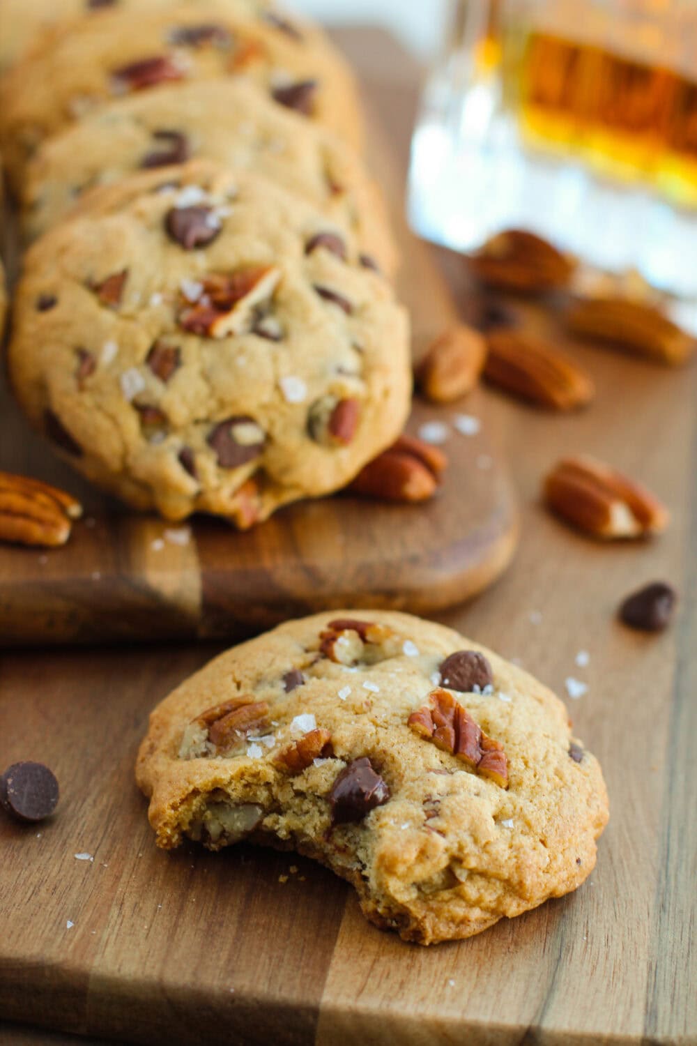 Chocolate chip cookies with pecans and one with a bite missing.