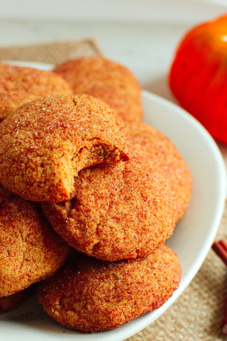 Bowl of pumpkin cookies with a bite missing from the top one.