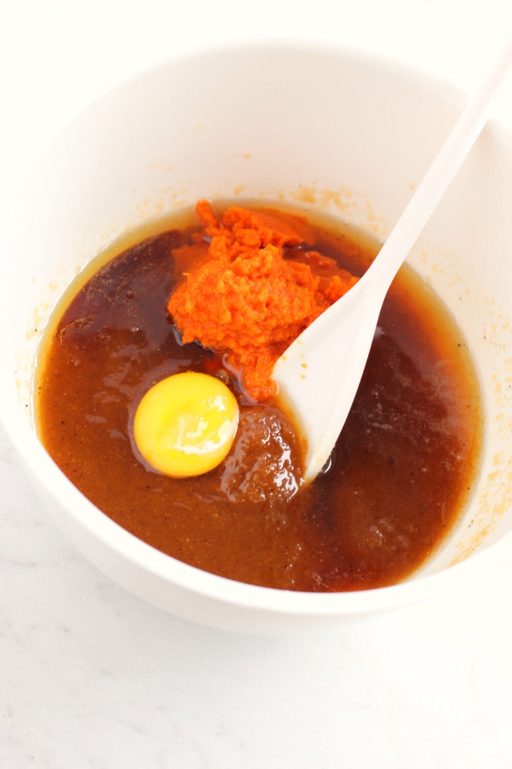 Egg and pumpkin in a mixing bowl. 