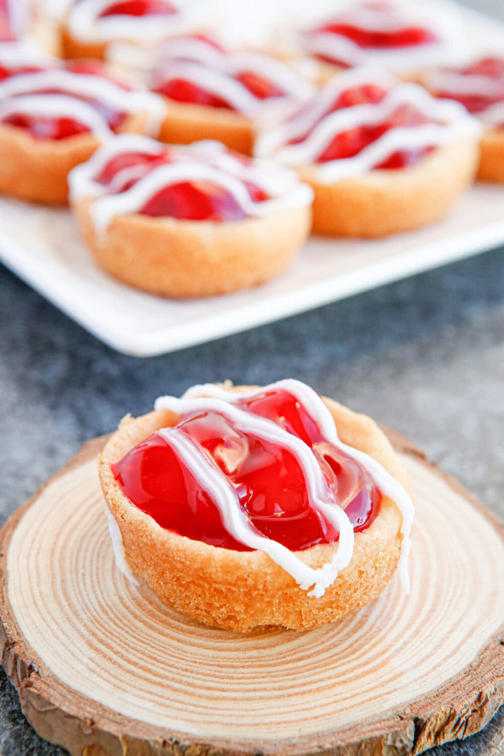 A cherry pie cookie on a wood slice with the rest in the background. 