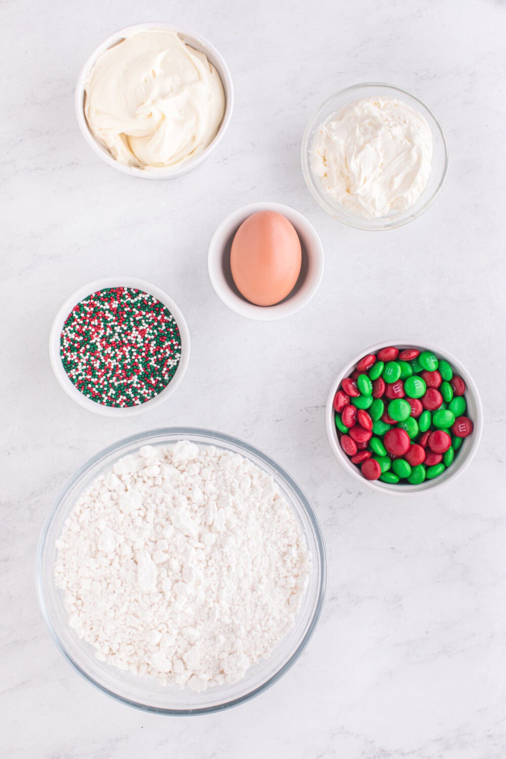 Egg, M&Ms, sprinkles, flour, and other ingredients for sugar cookie pie.