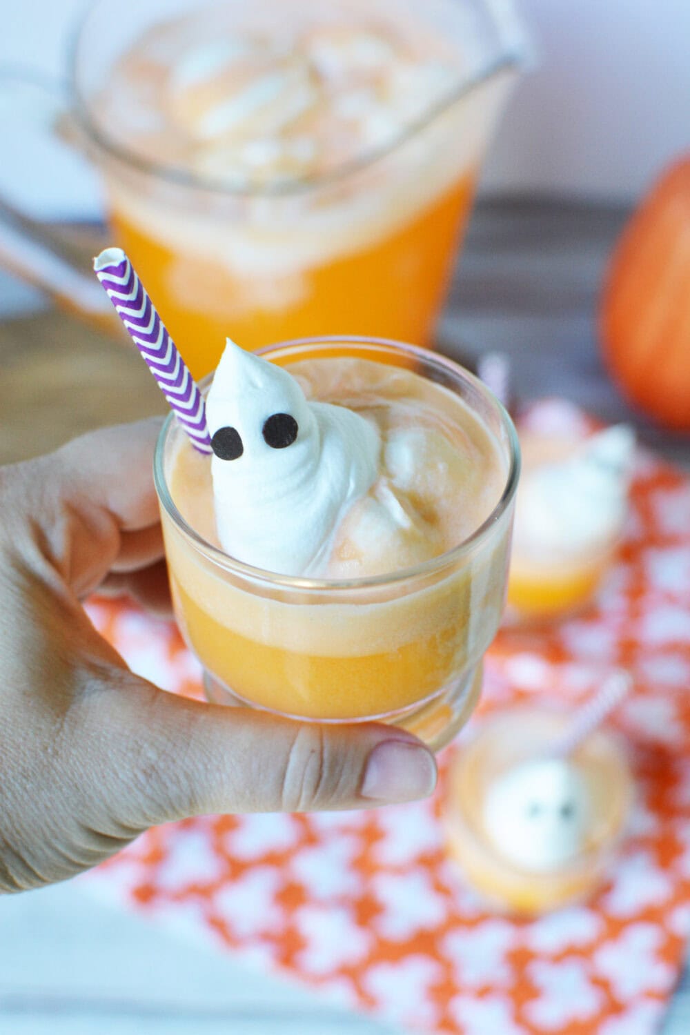 Holding a cup of orange ice cream punch with a ghost topping. 