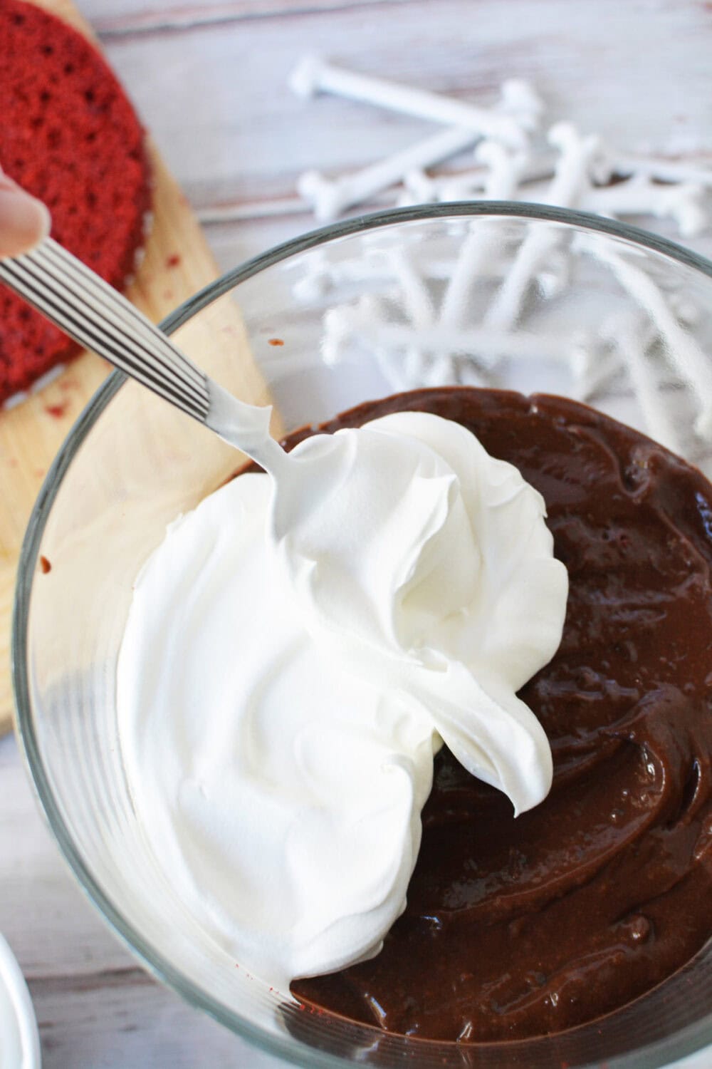 Adding whipped topping on top of pudding in a trifle bowl. 