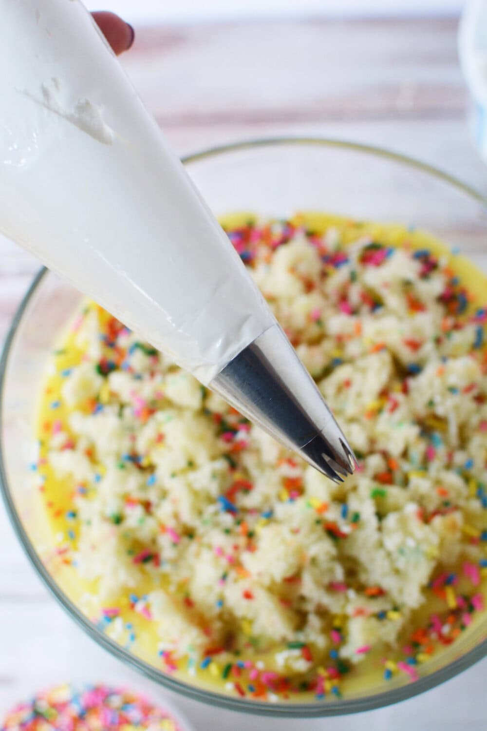 Whipped topping in a piping bag above a trifle. 