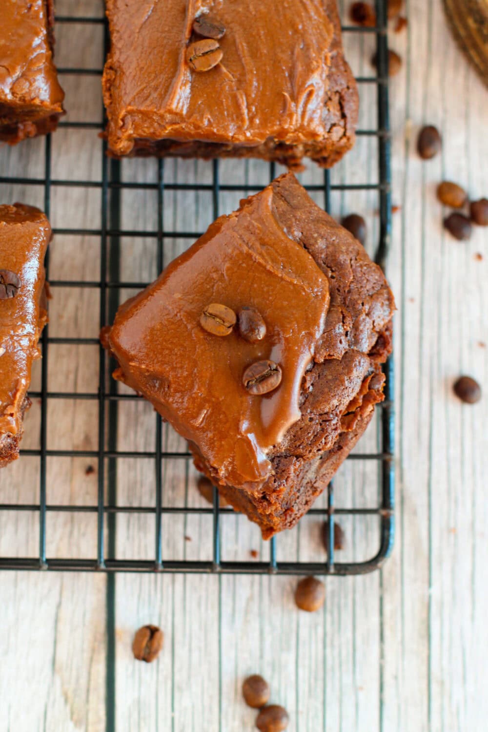 Fudgy brownies with frosting sliced on a wire rack. 