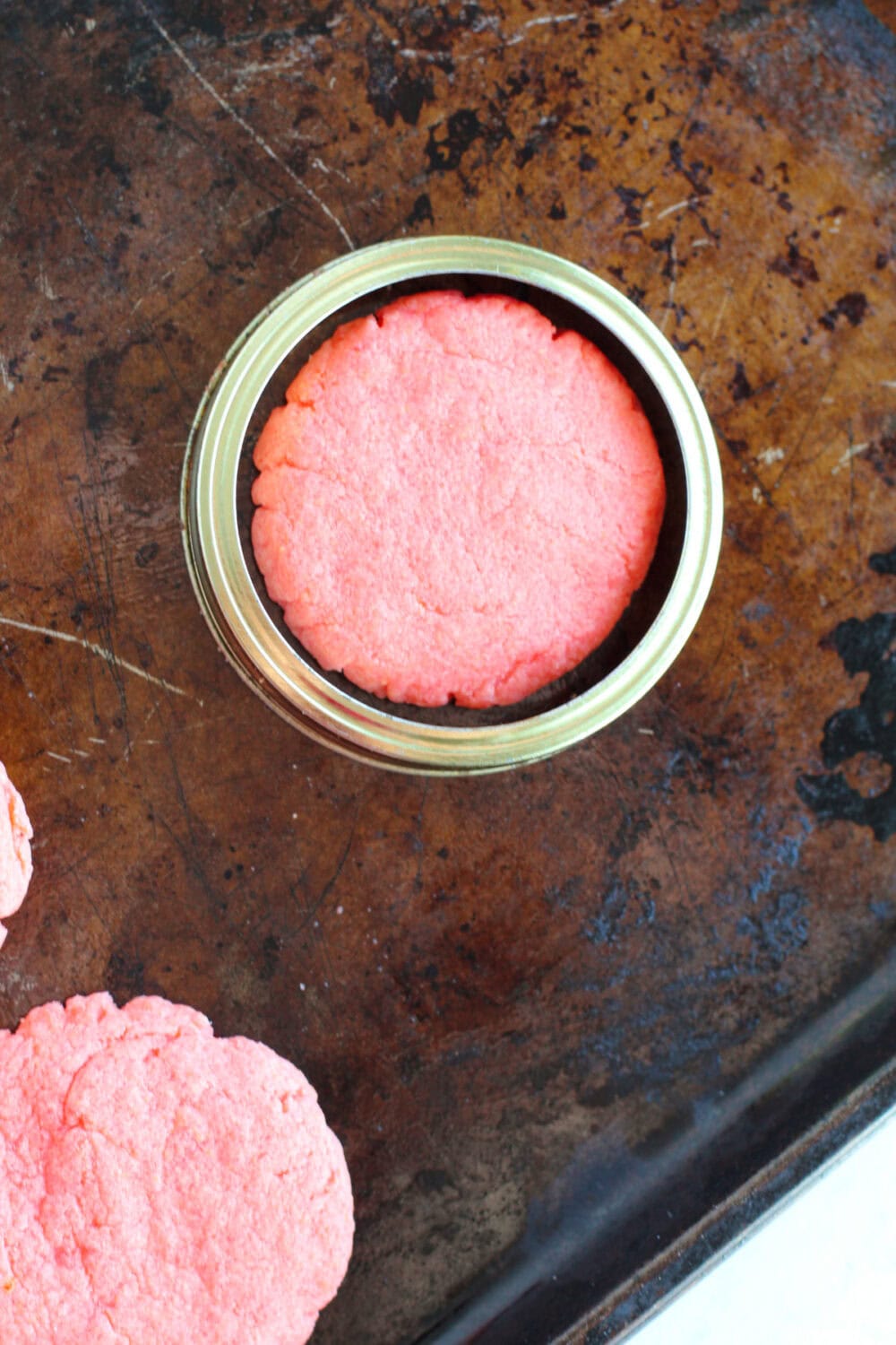 Mason jar ring around a cookie on a baking sheet. 