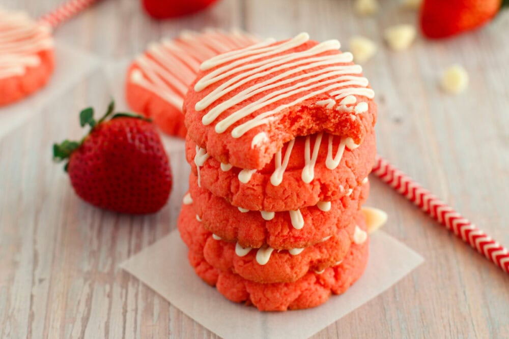 Strawberry cookies stacked with a bite taken out of the top one. 
