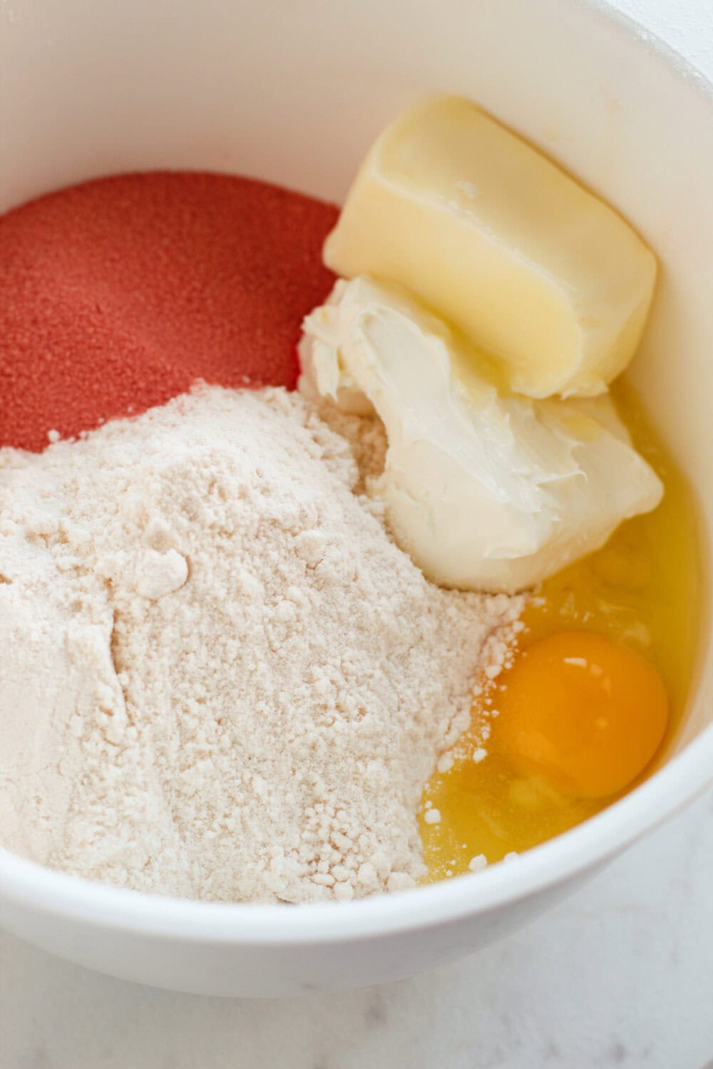 Cake mix, jello mix, butter, cream cheese, and egg in a bowl. 