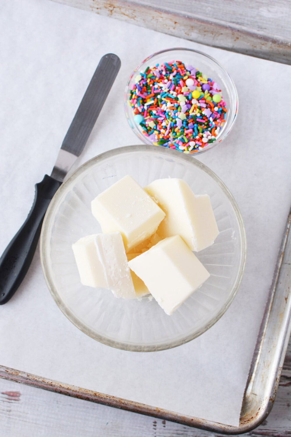 Almond bark and rainbow sprinkles in bowls.