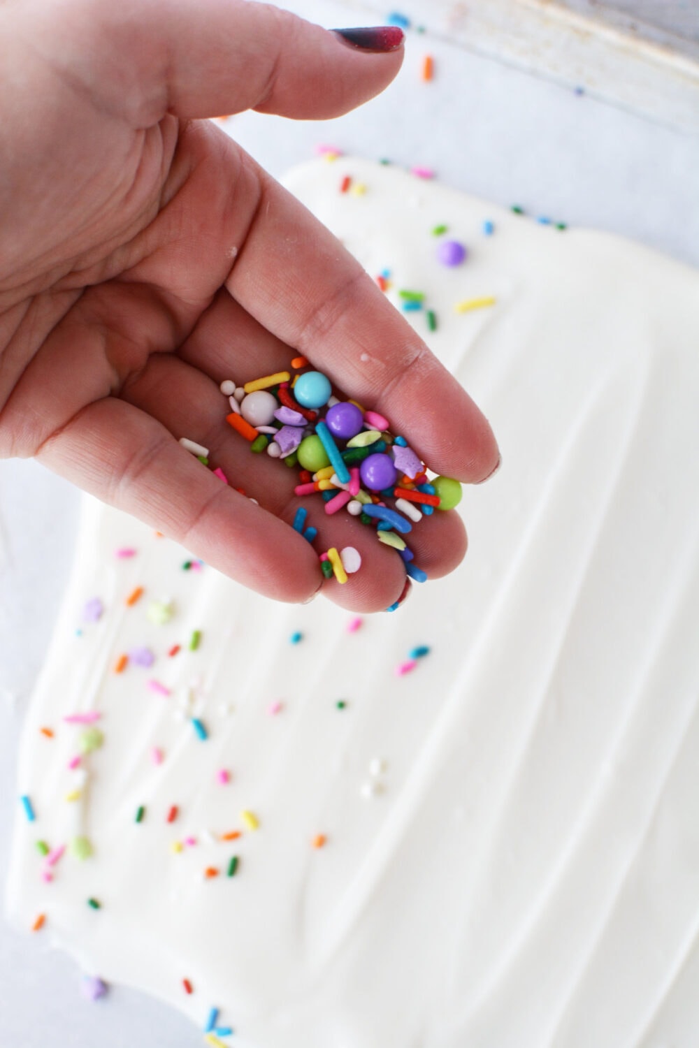 Sprinkling sprinkles onto melted almond bark.