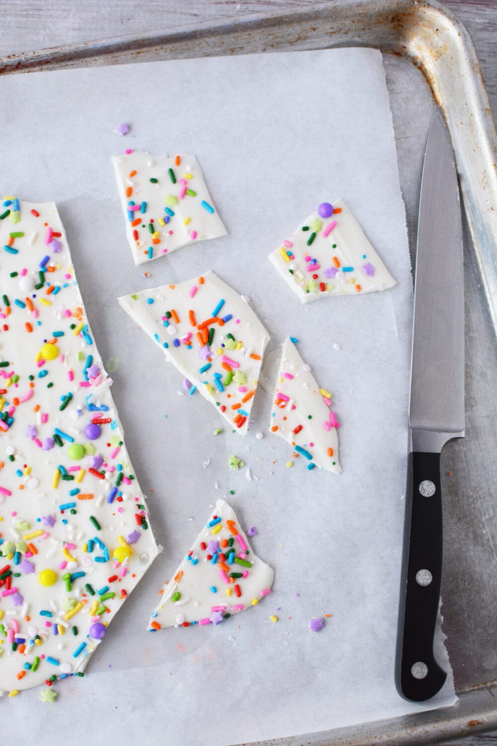 Cracked funfetti bark candy on a baking sheet.