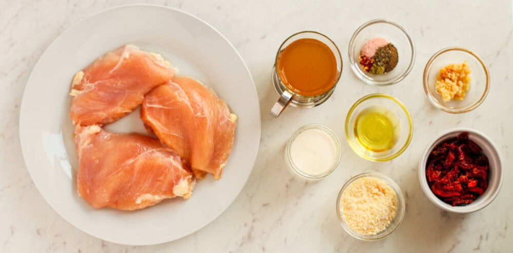 Chicken and spices and oils in bowls.
