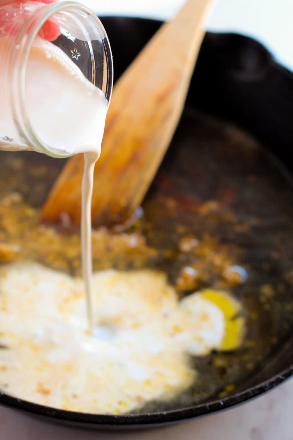 Pouring heavy cream into a skillet.
