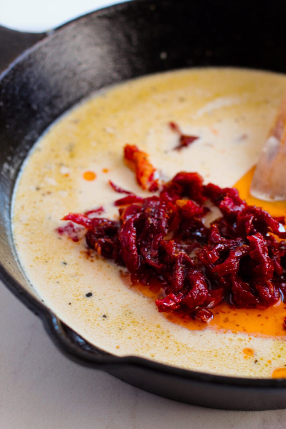 Sun-dried tomatoes in a cream sauce in a skillet.