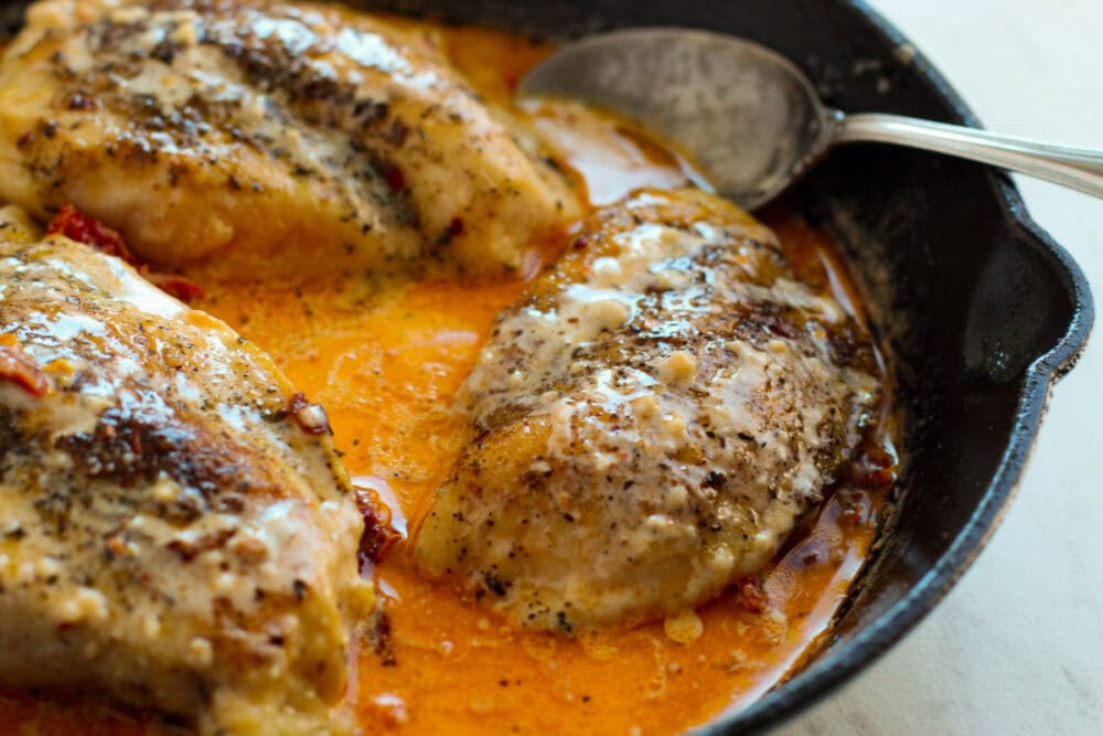 Chicken breasts in a skillet with marry me chicken cream sauce.